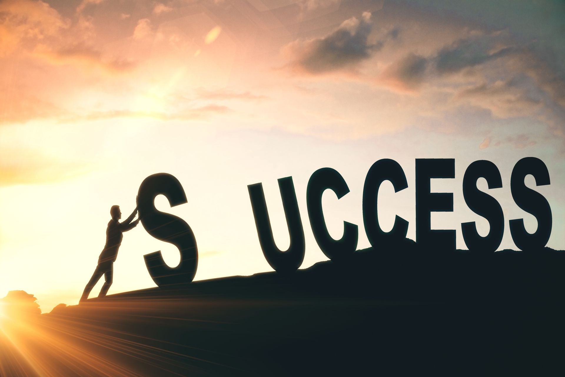 Silhoueete of person pushing against word SUCCESS